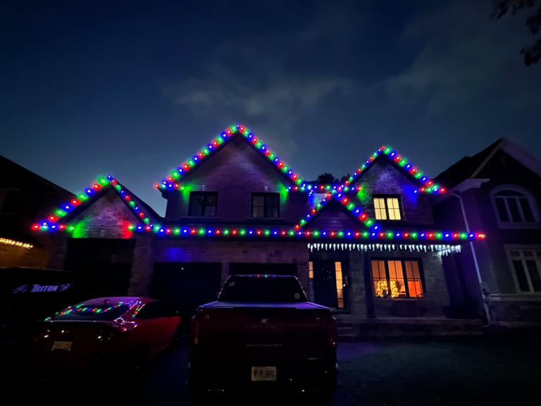 House decorated with colorful LED lights outlining rooflines and gables at night