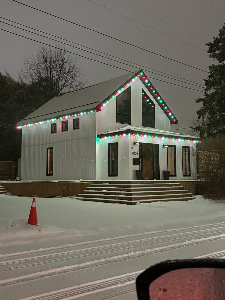 Modern white house decorated with colorful holiday lights and garland in snowy setting