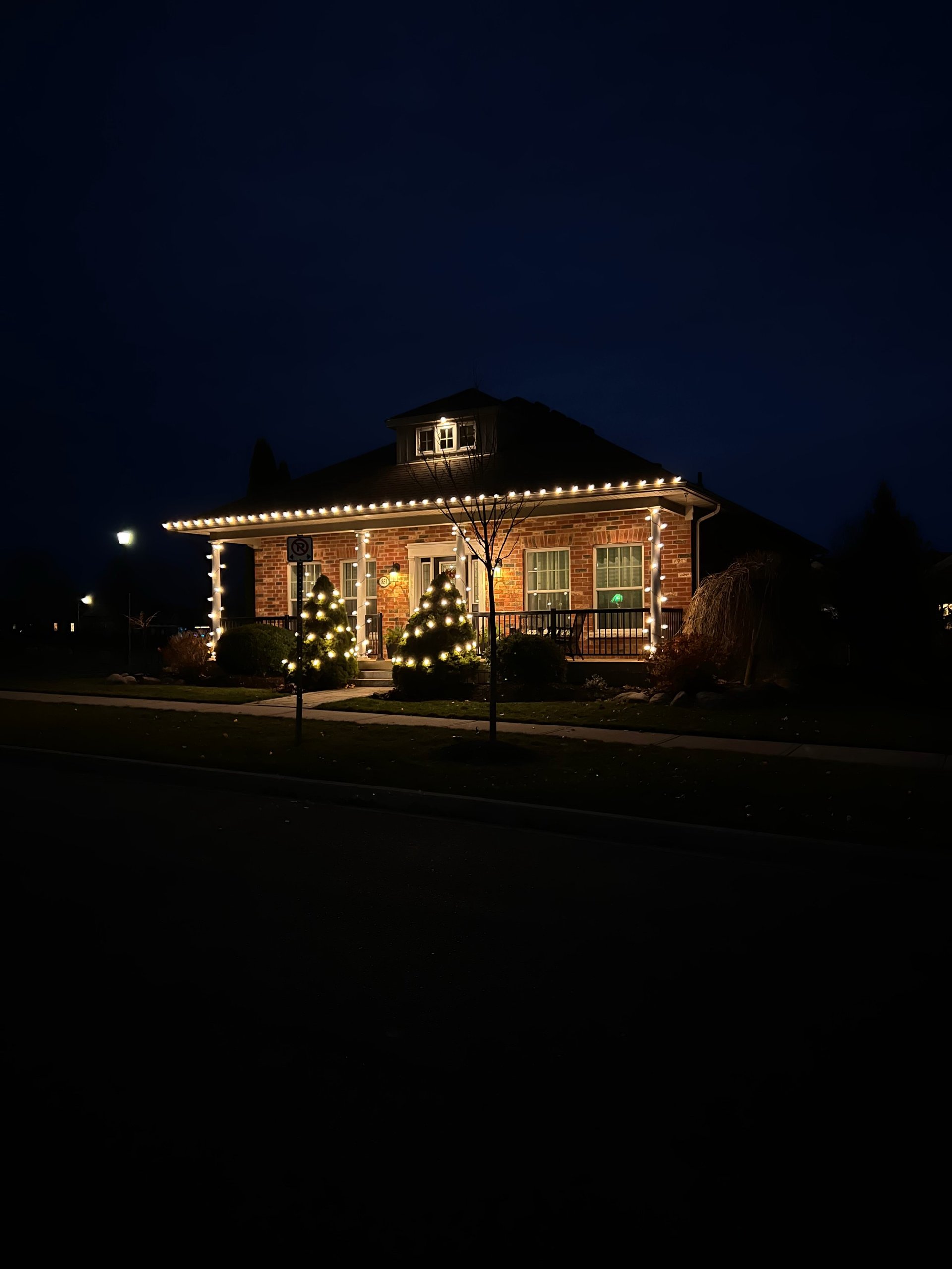 Red brick building decorated with warm white holiday lights at night against dark blue sky